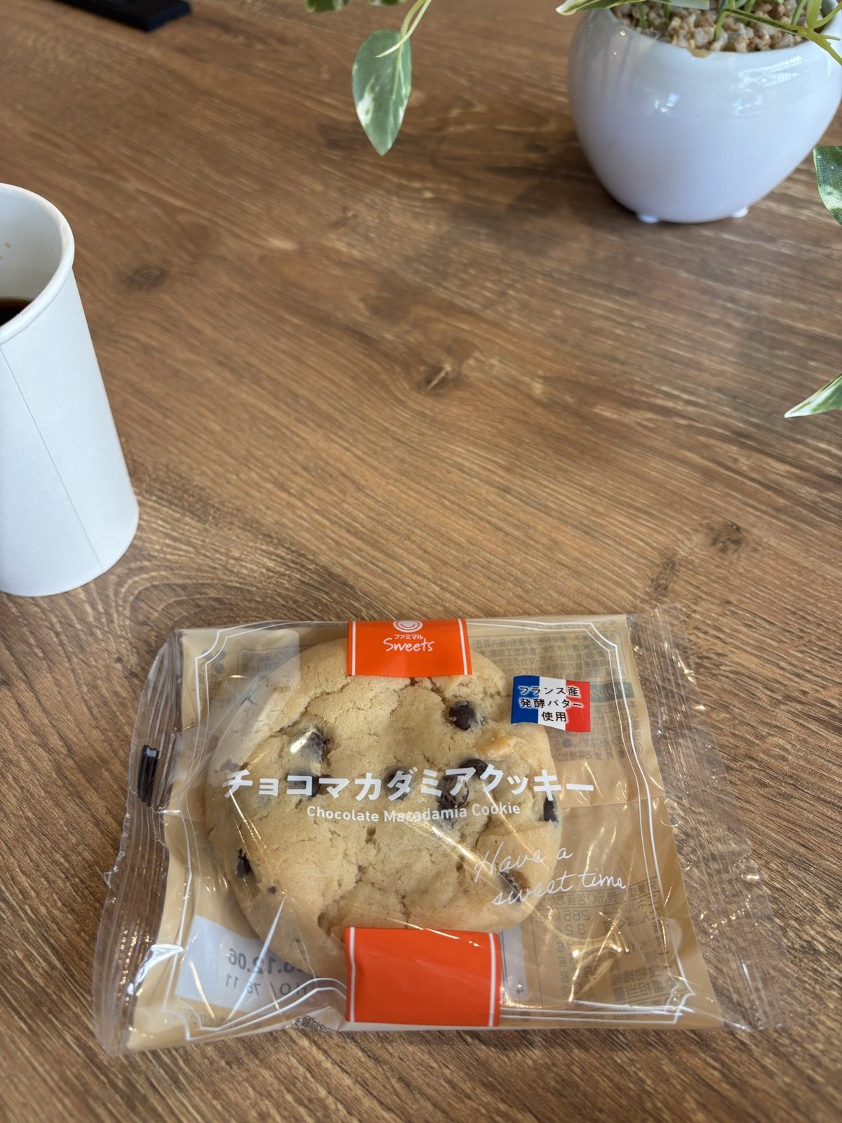 カフェのテーブルに置かれた、ファミマのチョコマカダミアクッキーとコーヒー